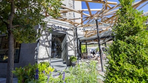 A café with outdoor seating, stone walls, and greenery. - Hotel Tudel (Escaldes-Engordany)