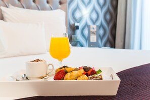 A breakfast tray with croissants, strawberries, and a glass of orange juice on a bed. - Ikonik Ramblas (Barcelona)