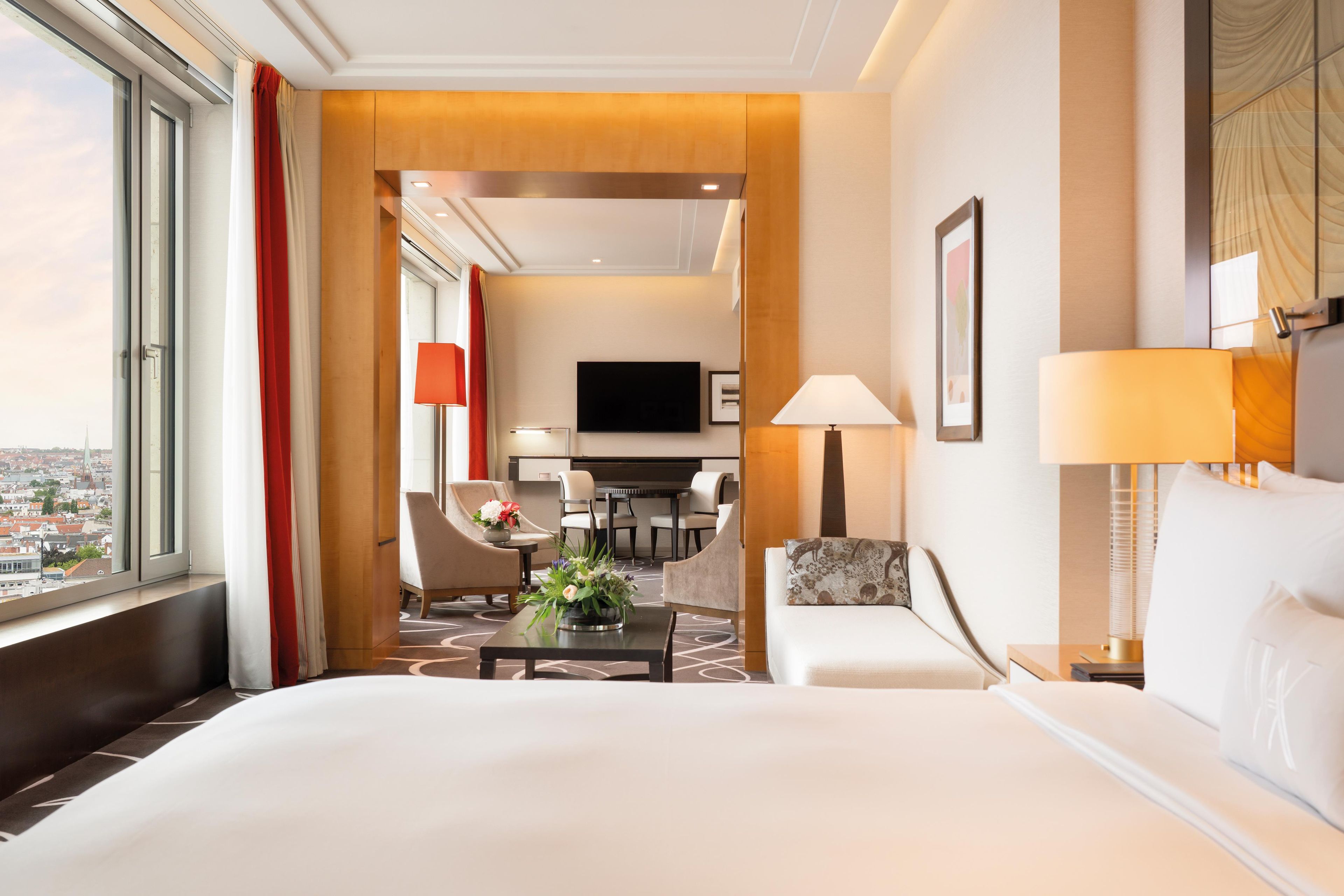 Habitación de hotel con una cama grande, un escritorio, una silla, televisión y vistas a la ciudad.