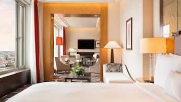 Habitación de hotel con una cama grande, un escritorio, una silla, televisión y vistas a la ciudad.