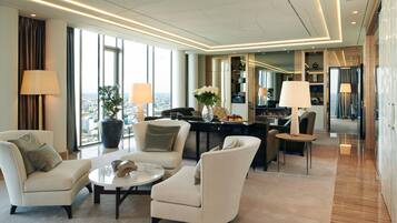 A modern hotel lobby with a seating area, a dining table, and a view of the city.