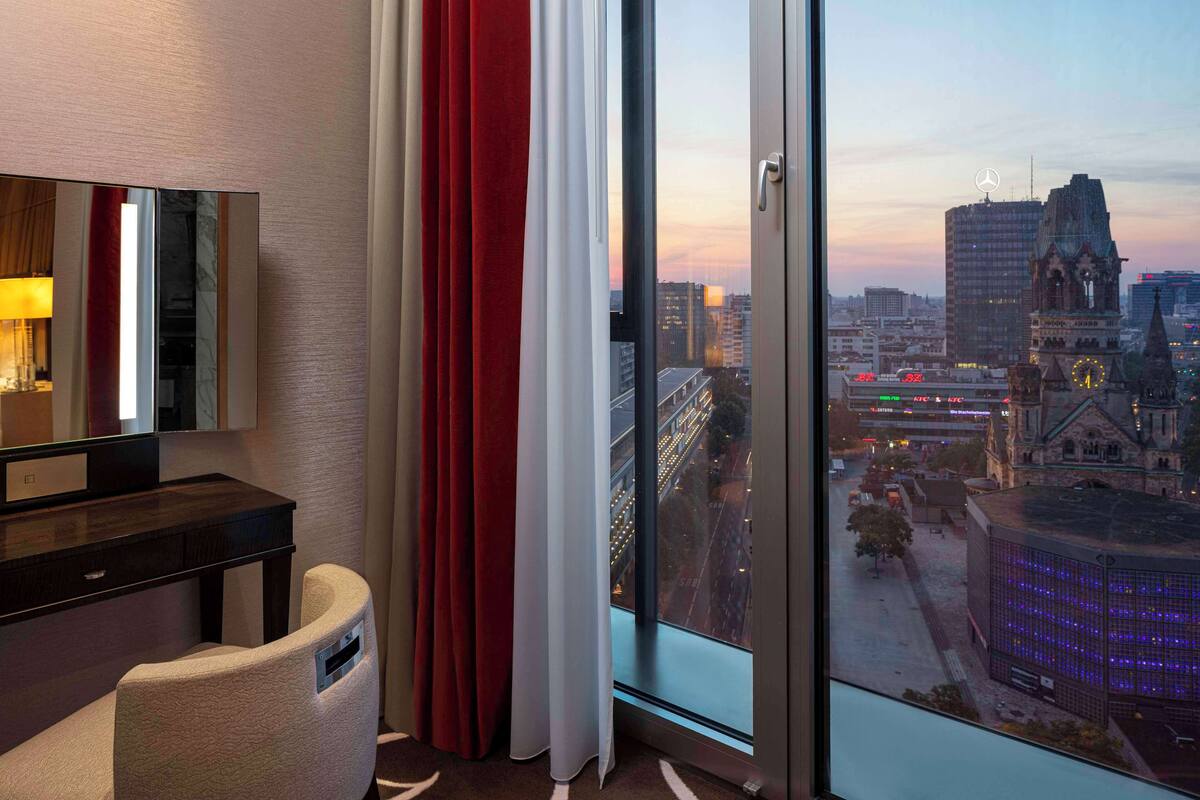 Una habitación de hotel con un ventanal grande, un escritorio y una silla.