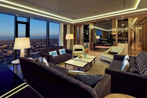 Una sala de estar moderna con vista a la ciudad, que incluye sofás, una mesa de centro y una chimenea.