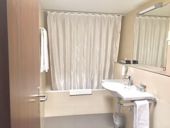 Un baño con lavamanos blanco, espejo y cortina de ducha.