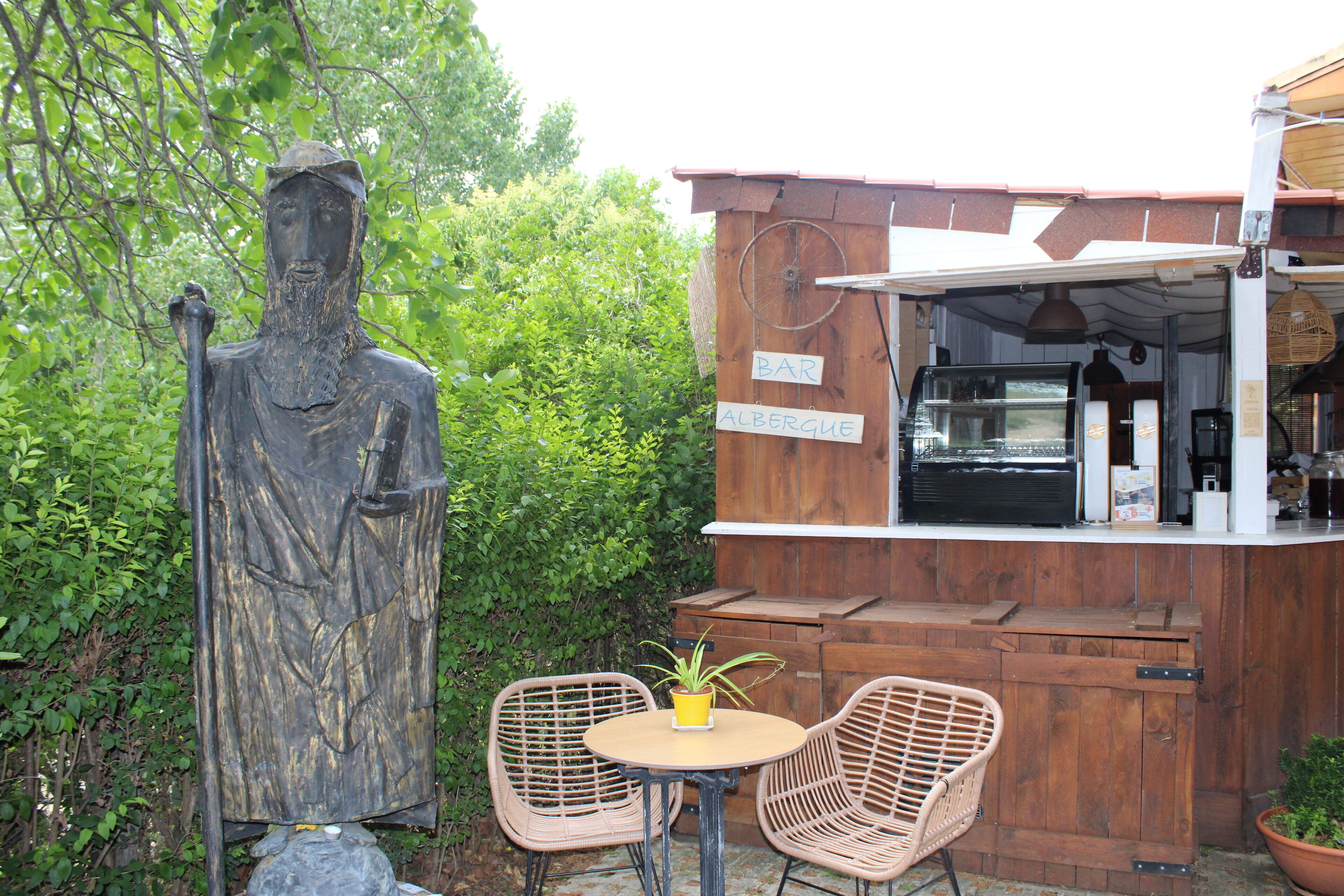 A rustic outdoor seating area with wicker chairs, a small round table, and a statue.
