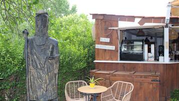 A rustic outdoor seating area with wicker chairs, a small round table, and a statue.