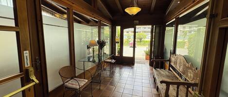 A corridor with a wooden ceiling, tiled floor, and glass doors leading to an outdoor area.