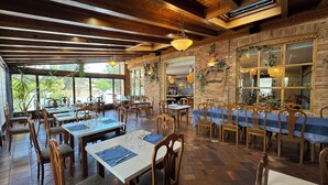 Ein Restaurant mit Holztischen und -stühlen, Backsteinwänden und hängenden Lampen.