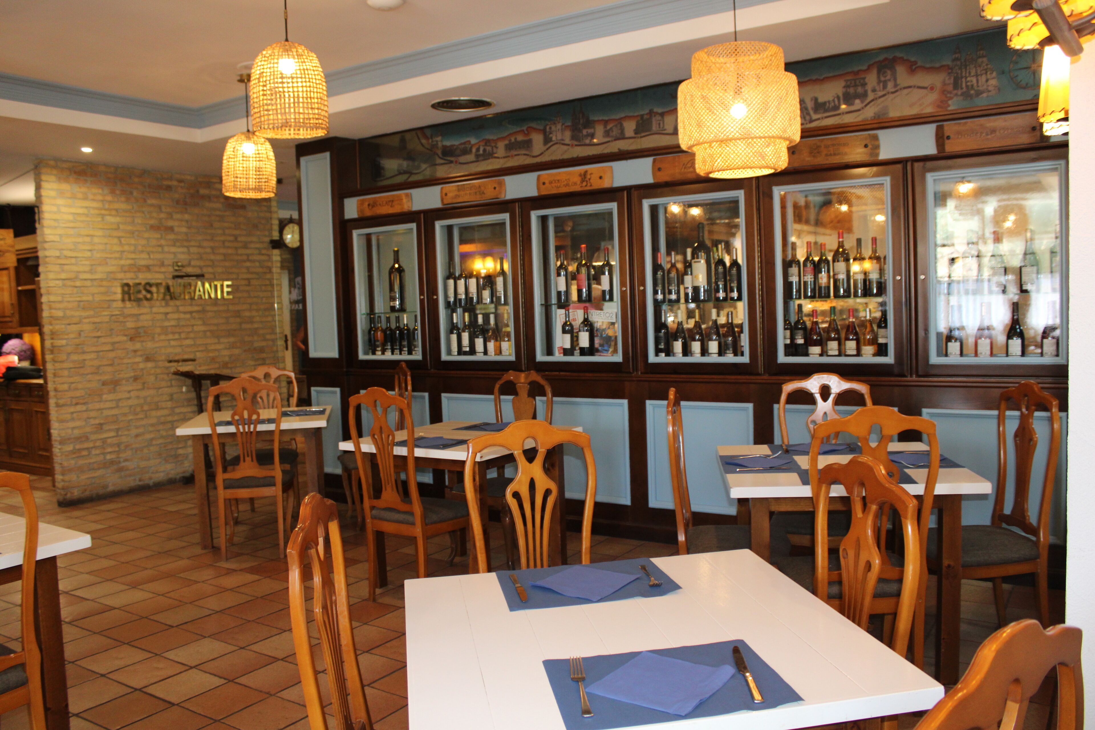 A restaurant interior with wooden chairs, tables, and a wine display.