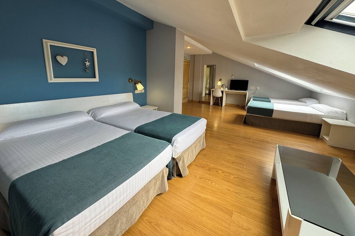 Una habitación de hotel moderna con dos camas, un escritorio y un televisor.