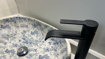 A bathroom with a white sink featuring blue floral patterns and a black faucet.