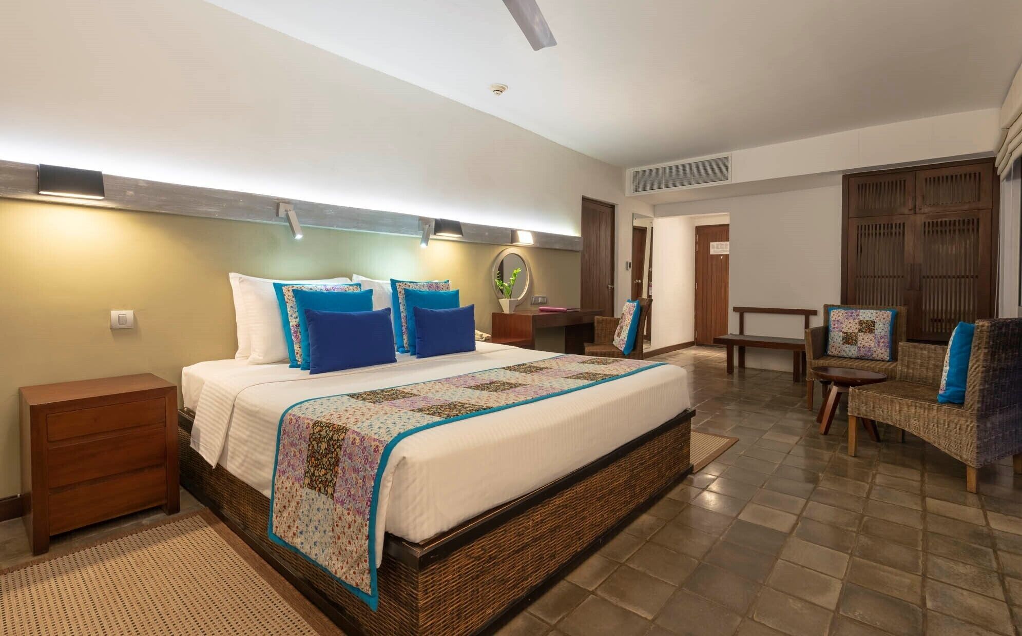 A bedroom with a large bed, a nightstand, a chair, and a small table.