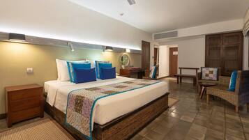 A bedroom with a large bed, a nightstand, a chair, and a small table.