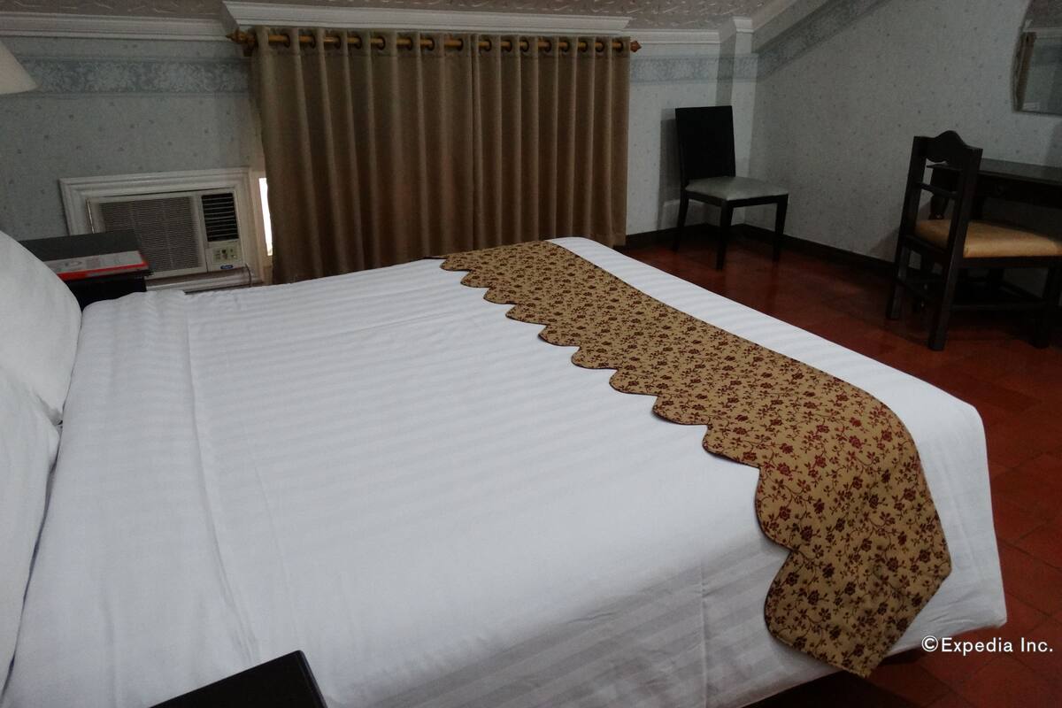 Habitación de hotel con una cama grande, un escritorio, una silla y un radiador.