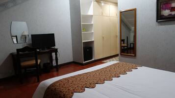 Une chambre d’hôtel comprenant un lit, un bureau avec une télévision, une armoire et un miroir.