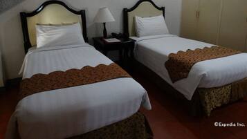 A hotel room with two beds, a nightstand with a lamp, a framed picture on the wall, and a wardrobe.