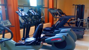 Un gimnasio con diversos equipos de ejercicio, incluyendo cintas de correr y elípticas.