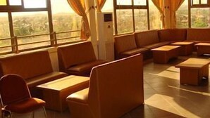 Una habitación de hotel con un ventanal grande, un sofá, una silla y una pequeña mesa.