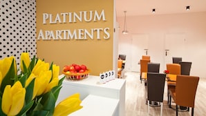 A reception area with a sign reading "PLATINUM APARTMENTS," a fruit bowl, and modern furniture. - Platinum Apartments Aparthotel (Poznan)