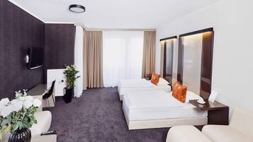 Hotellihuone, jossa on sänky, työpöytä, tuoli, televisio ja suuri ikkuna, jossa on verhot.