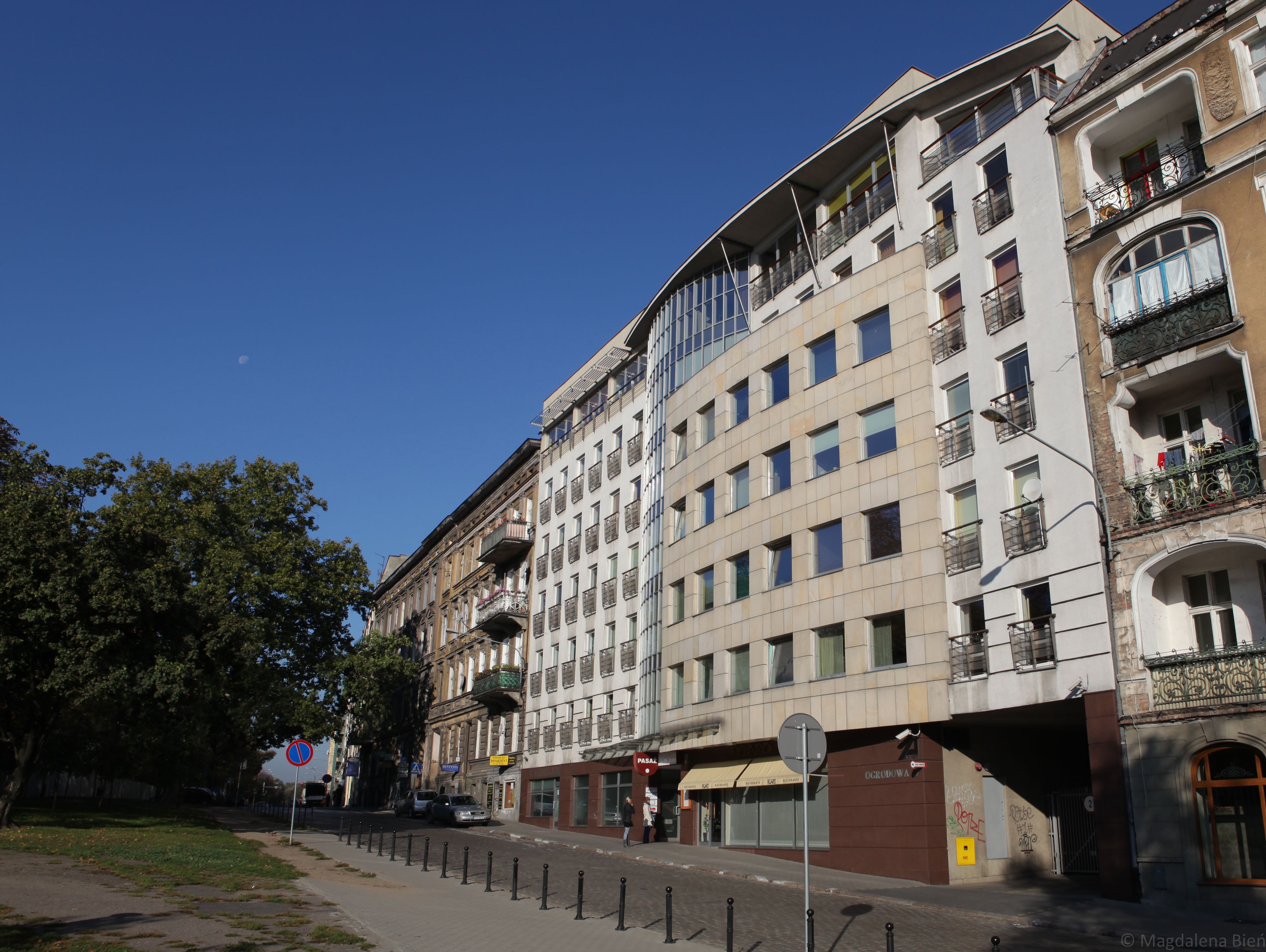 Un edificio a più piani con spazi residenziali e commerciali, caratterizzato da balconi, ampie finestre e un negozio ben visibile.