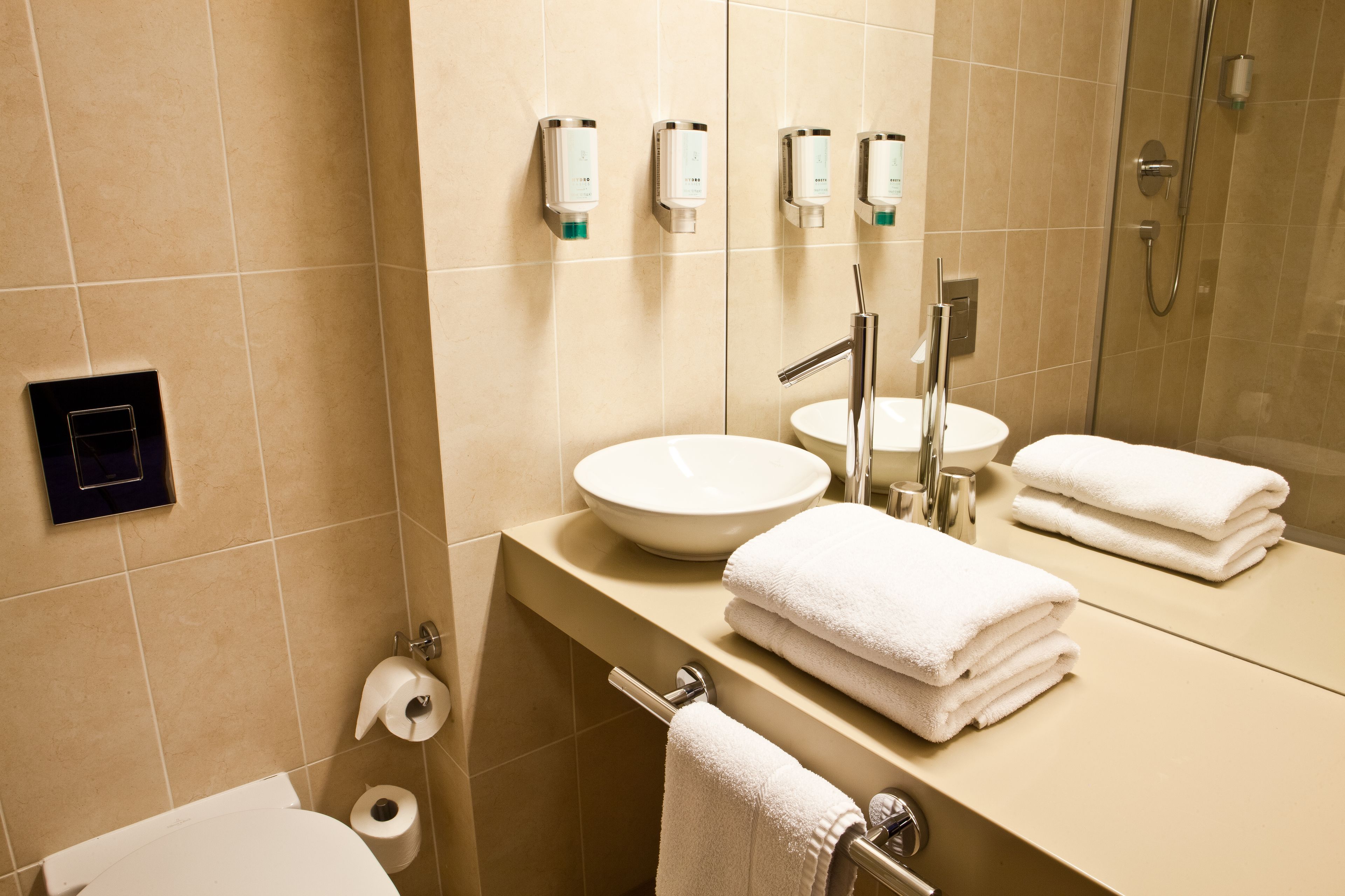 A modern bathroom with a large sink, two mirrors, and a glass shower enclosure.