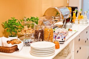 A buffet with various food items, including pastries, cereals, and beverages.
