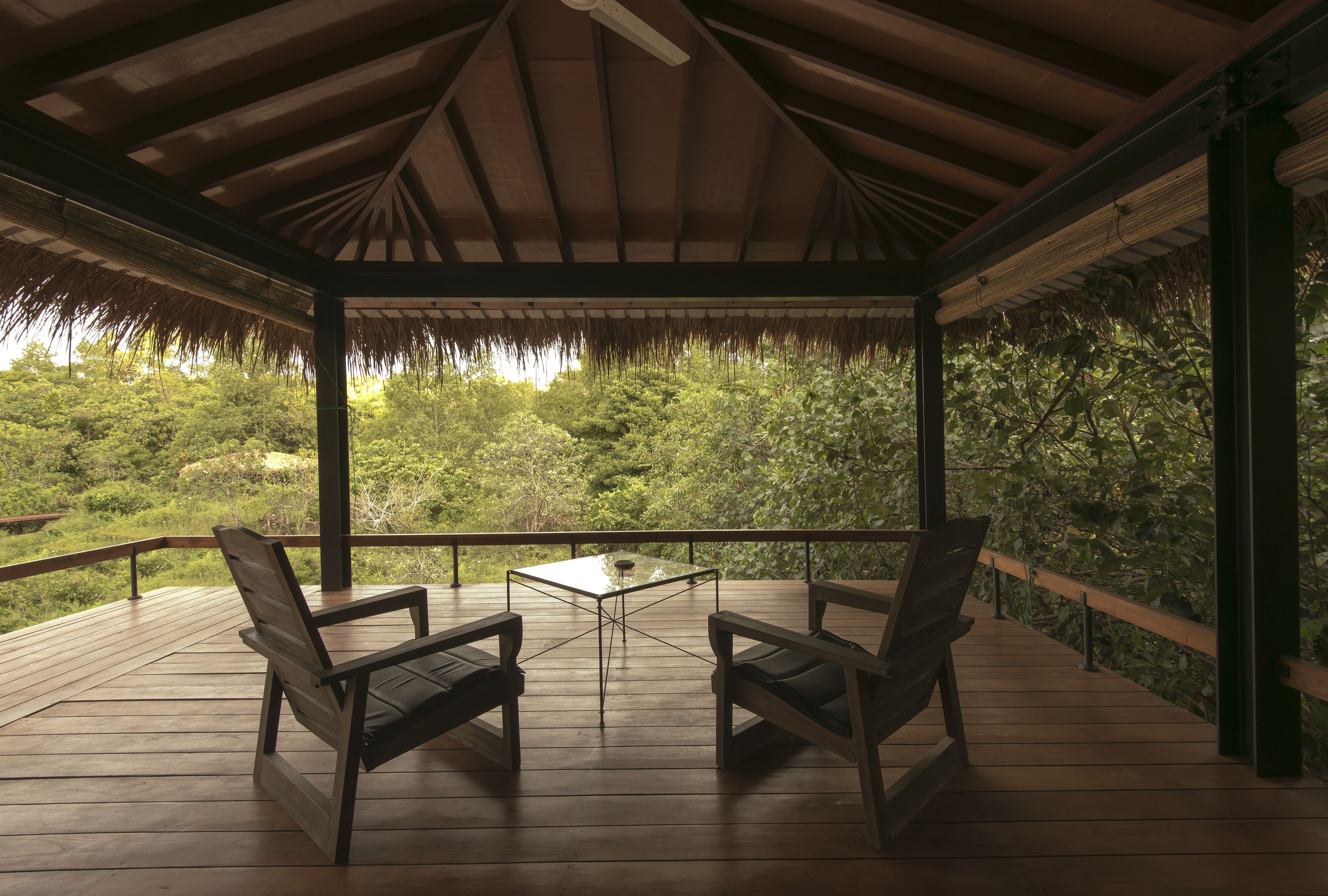 A wooden deck with two chairs and a table, overlooking a lush green landscape.