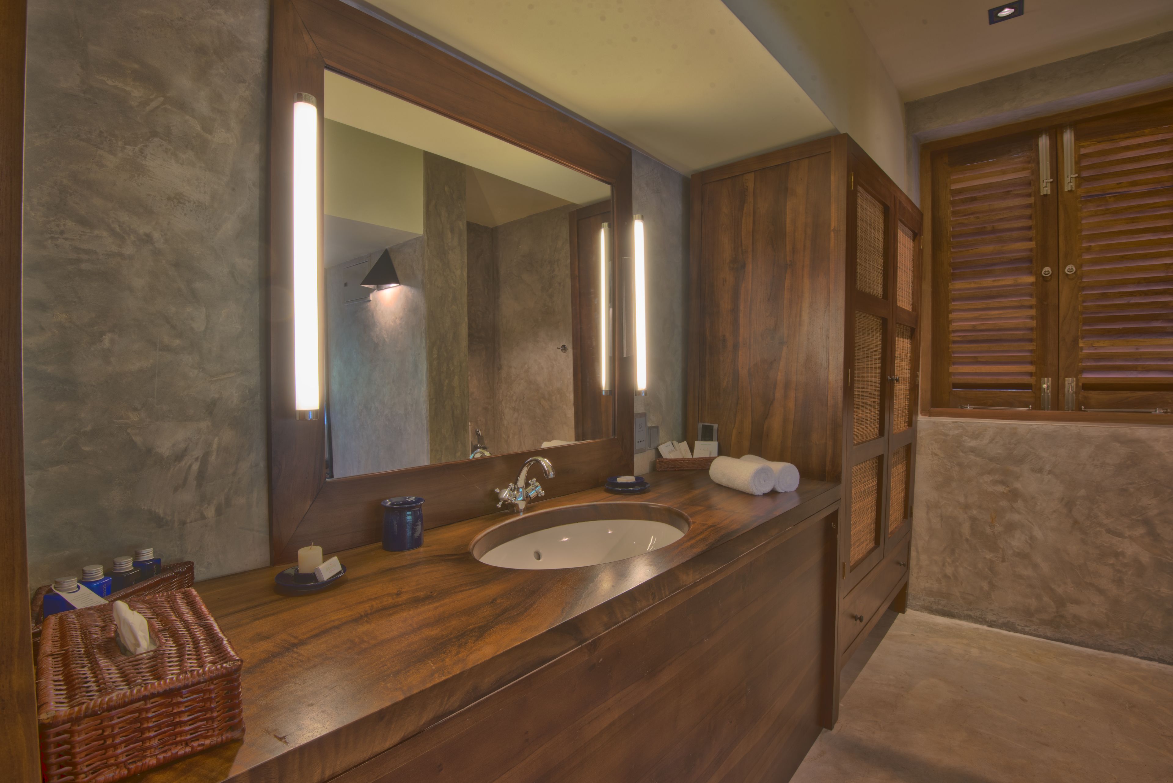 Un baño con tocador de madera, un espejo grande, un lavabo y un perchero para toallas.