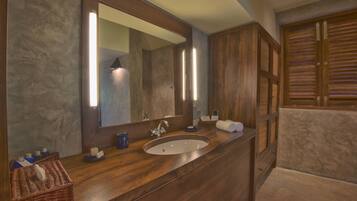 Un baño con tocador de madera, un espejo grande, un lavabo y un perchero para toallas.