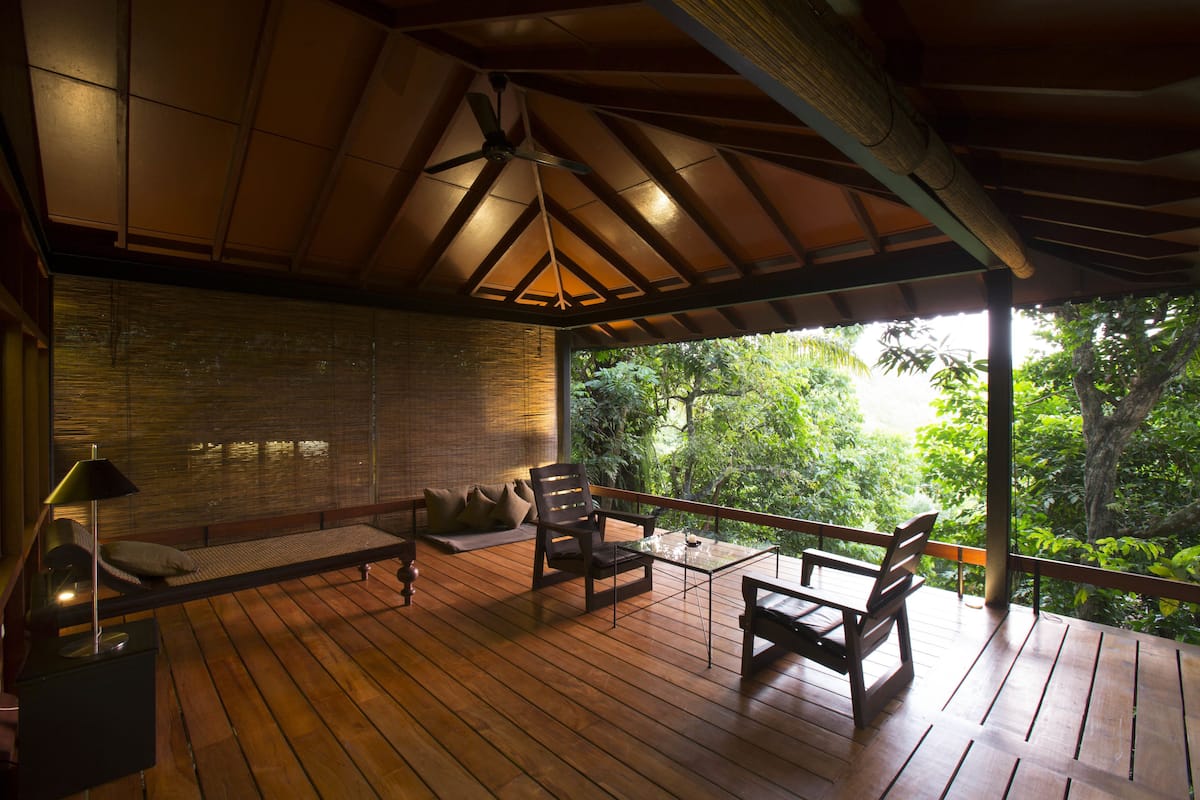A wooden deck with a ceiling fan, a sofa, and a table with chairs.