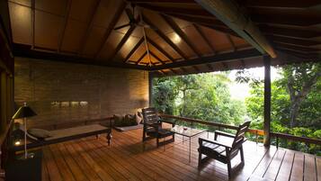 A wooden deck with a ceiling fan, a sofa, and a table with chairs.
