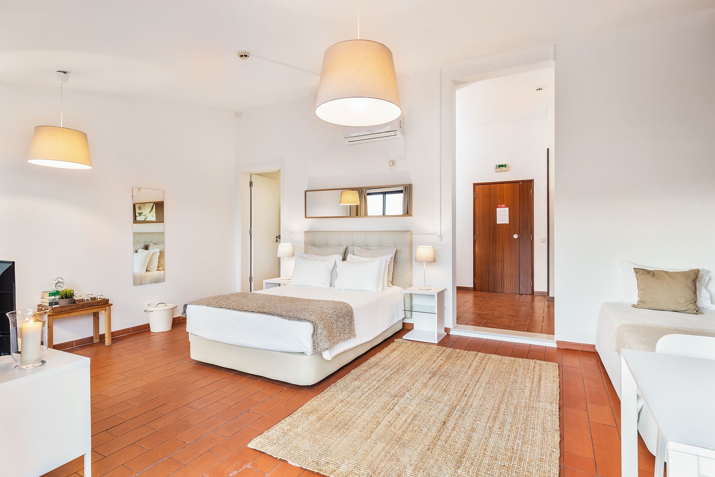 A modern bedroom with a large bed, bedside tables, a mirror, and a TV.