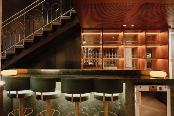 Un espace bar avec un escalier, des tabourets de bar et un comptoir.