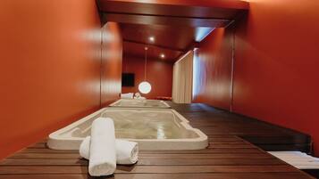 Une salle de spa avec un plancher en bois, un jacuzzi et une serviette.