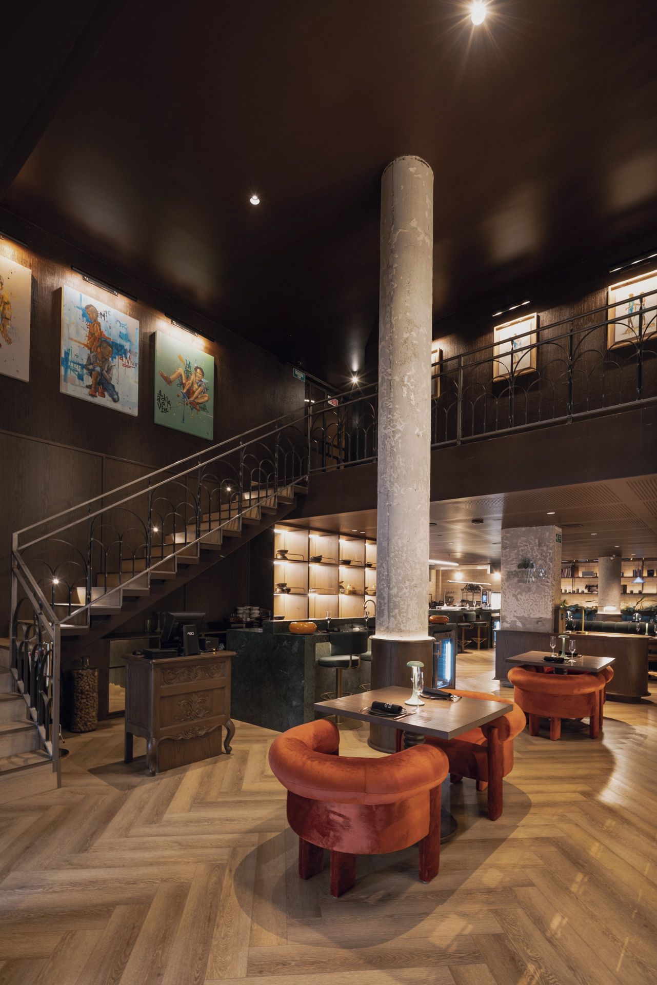 A spacious lobby with a central column, a staircase, and a bar area.