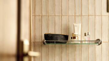 Un baño con un estante de vidrio que sostiene una bolsa negra y artículos de aseo.