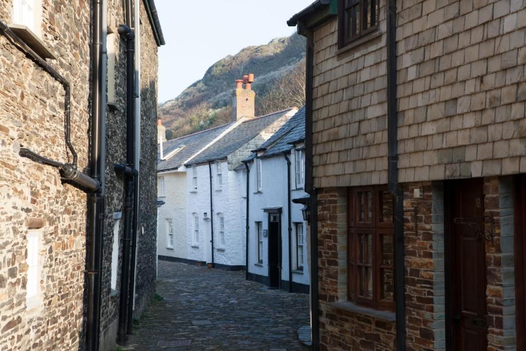 Una estrecha calle empedrada flanqueada por edificios de piedra tradicionales con fachadas blancas y contraventanas oscuras.