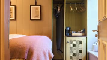 Un dormitorio con cama, armario y una pequeña zona de kitchenette.