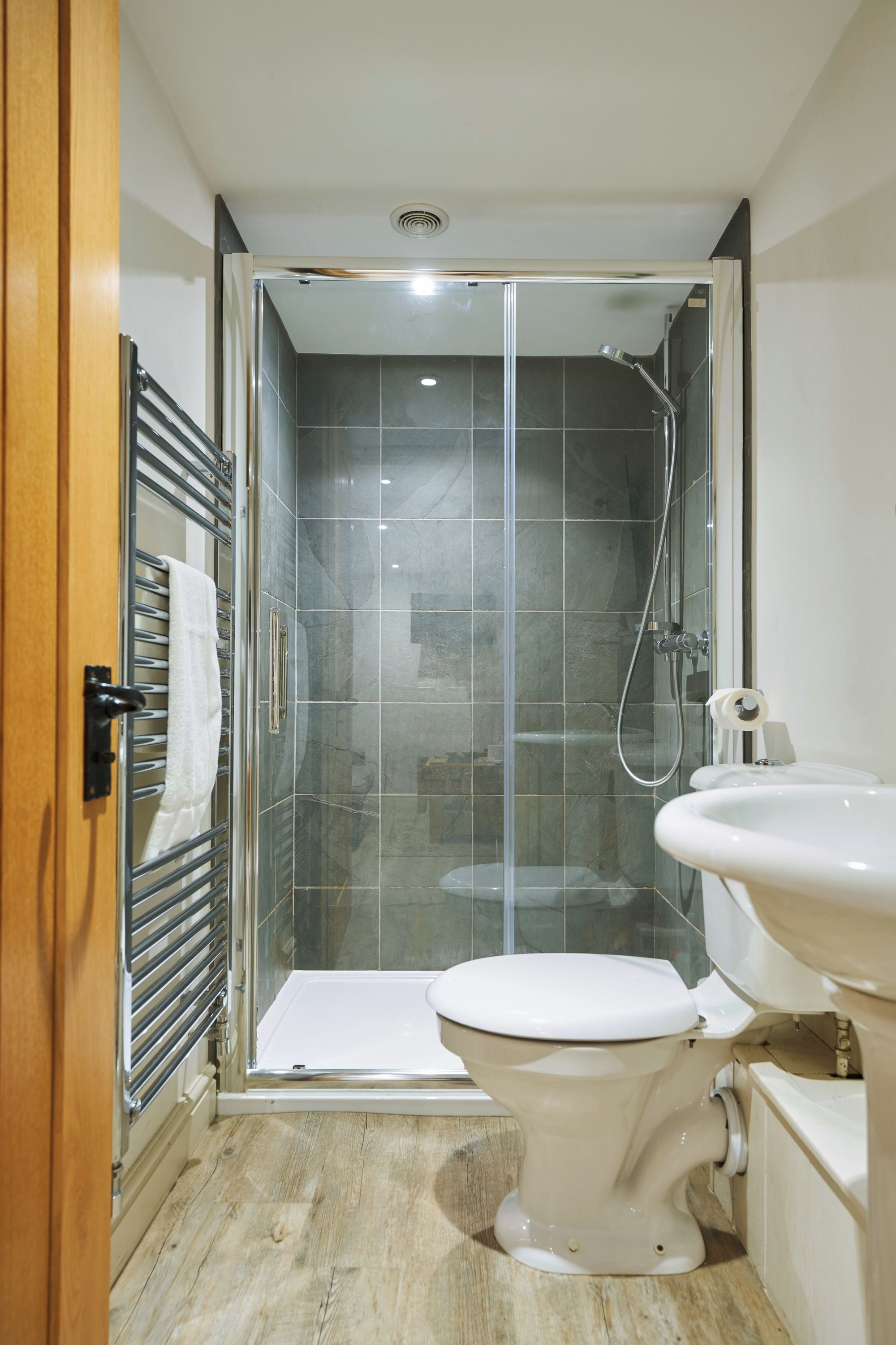 A modern bathroom with a glass-enclosed shower, a white toilet, and a sink.
