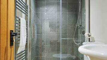 A modern bathroom with a glass-enclosed shower, a white toilet, and a sink.