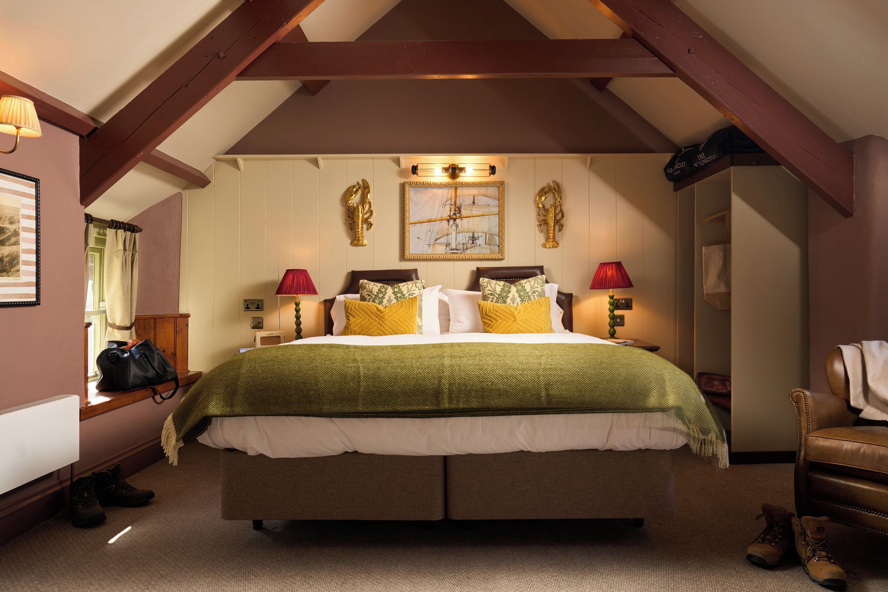 Uma cama de casal com um cobertor verde, duas luminárias e um quadro na parede.