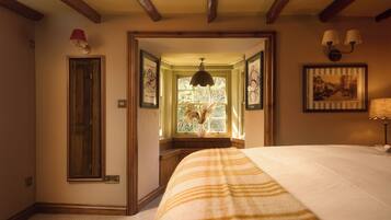 A bedroom with a large bed, a window with a view, a door, and a chandelier.
