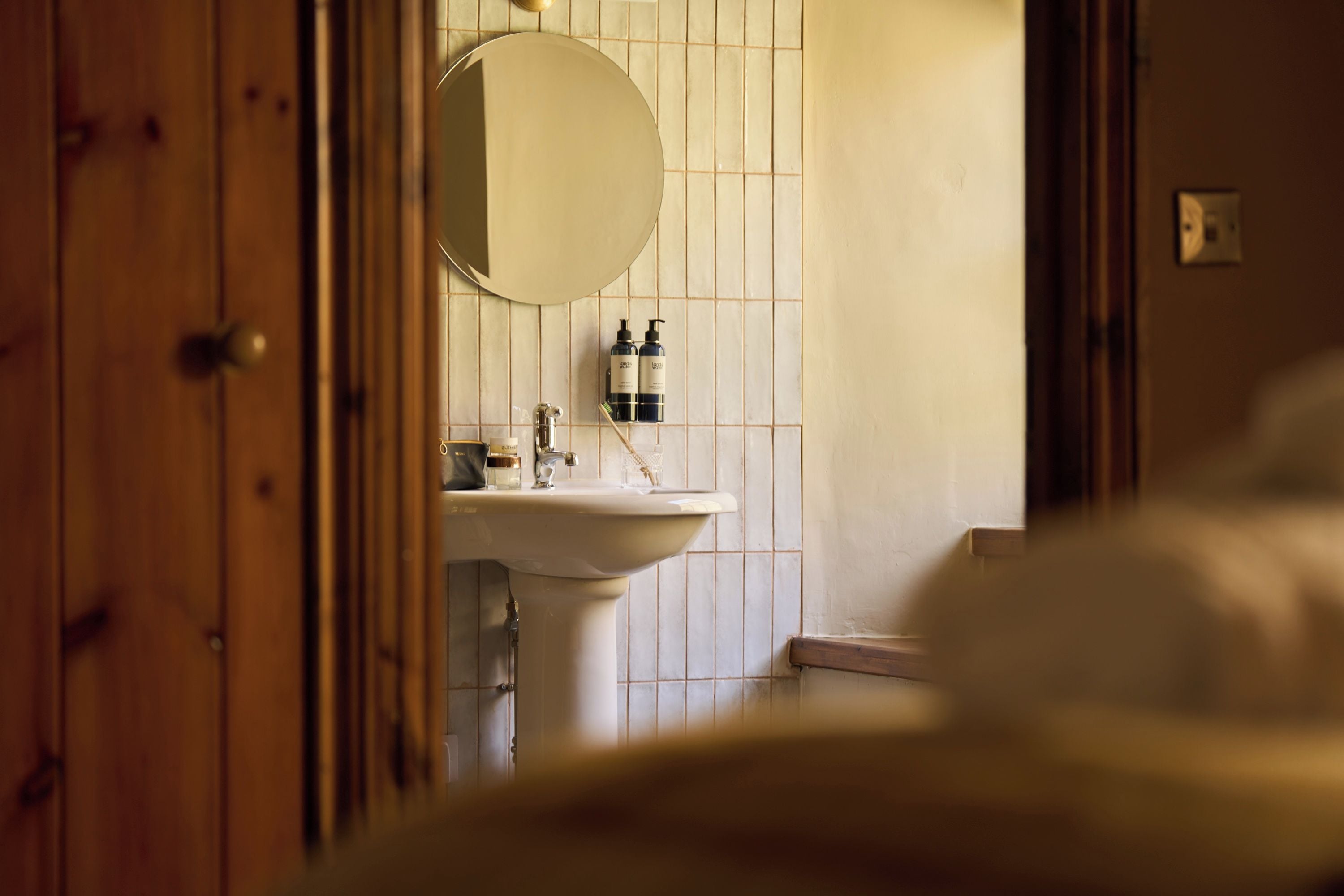 Un baño con un lavabo blanco, un espejo y artículos de tocador en la pared.