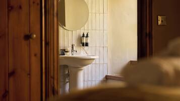 Un baño con un lavabo blanco, un espejo y artículos de tocador en la pared.