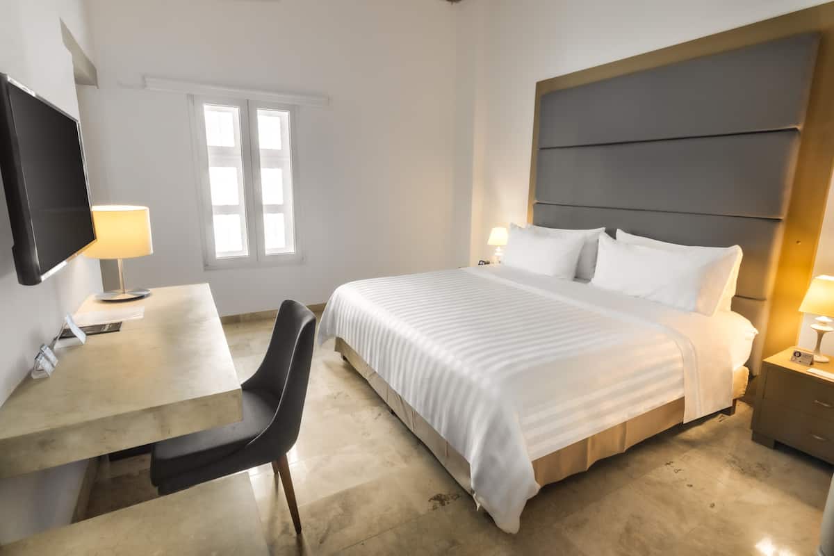A hotel room with a bed, bedside tables, a desk, and a chair.