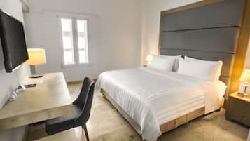 A hotel room with a bed, bedside tables, a desk, and a chair.
