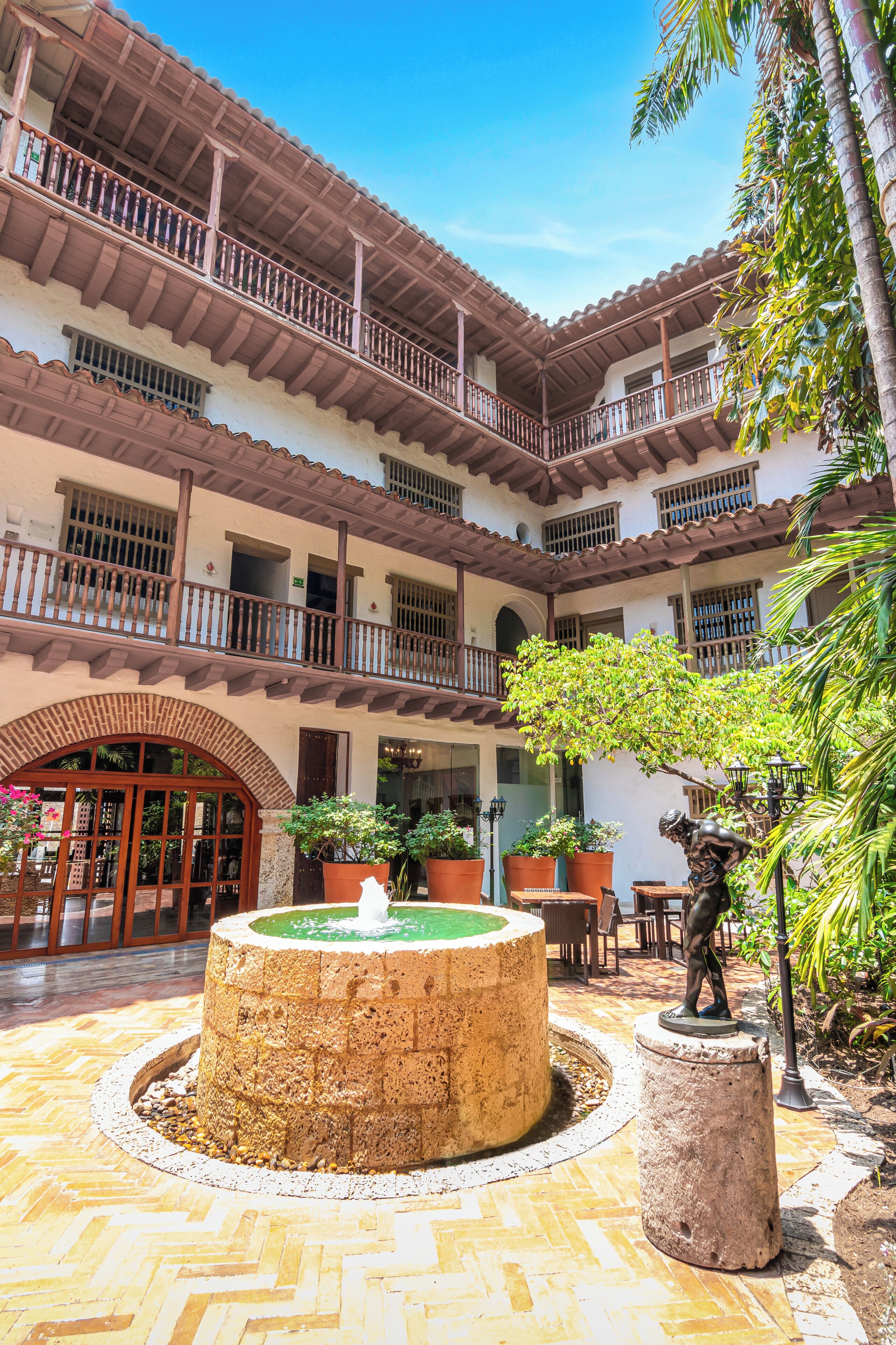 A courtyard with a fountain, potted plants, and a statue.