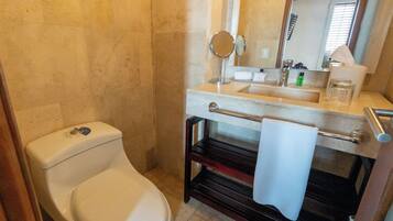 A bathroom with a toilet, sink, mirror, and towel rack.