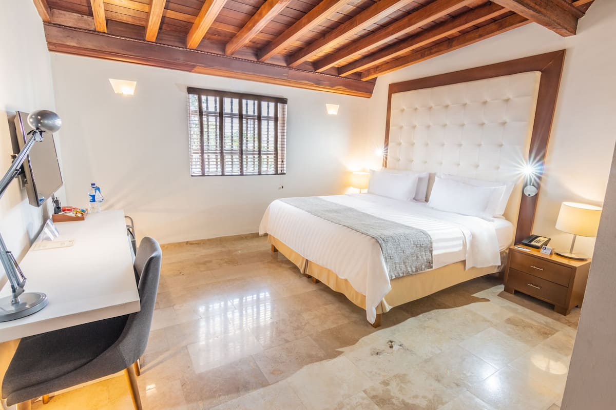 A bedroom with a bed, bedside tables, a desk, and a chair.